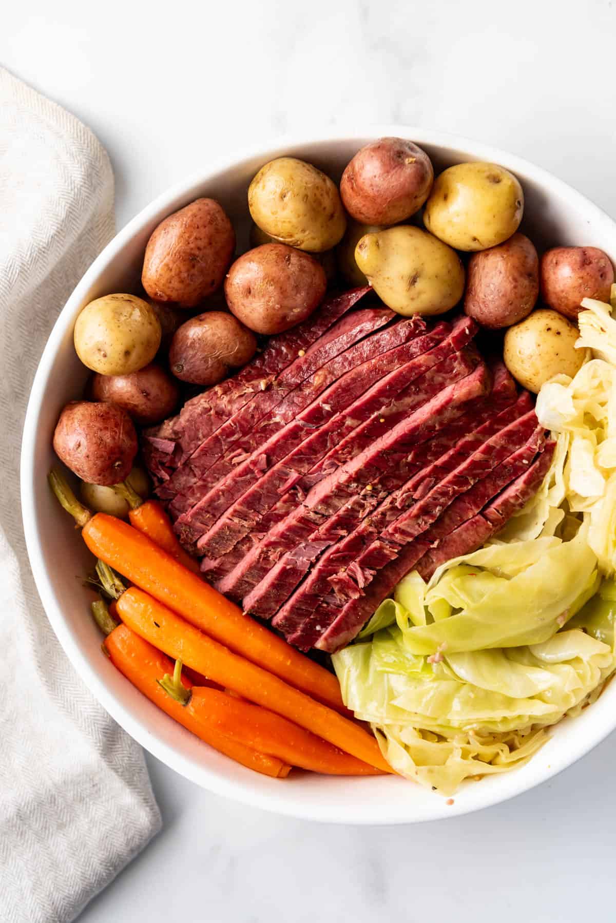 An image of a large plate of sliced corned beef and cabbage with potatoes and carrots.