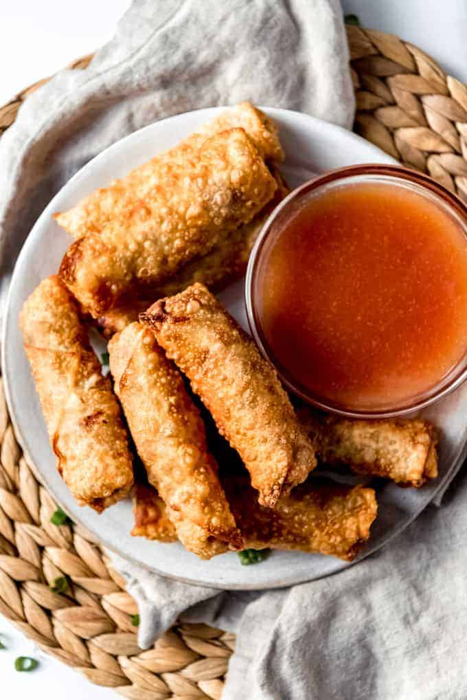 An image of crispy egg rolls next to sweet and sour dipping sauce.