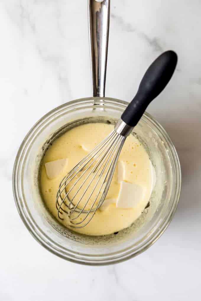 An image of butter melting into lemon curd in a glass bowl.