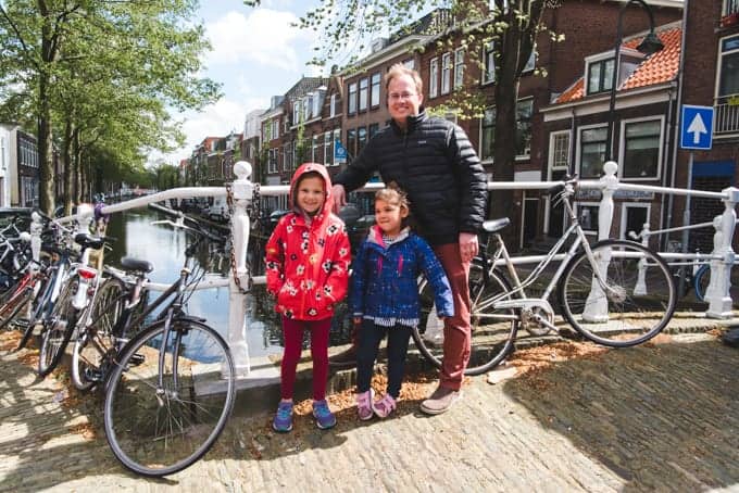 a man and 2 daughters standing next to bikes on a bridge