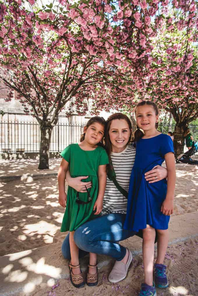 An image of a mother and daughters in front of pink blossoms in Paris in Spring.