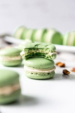 An image of a homemade pistachio macaron with a bite taken out of it.