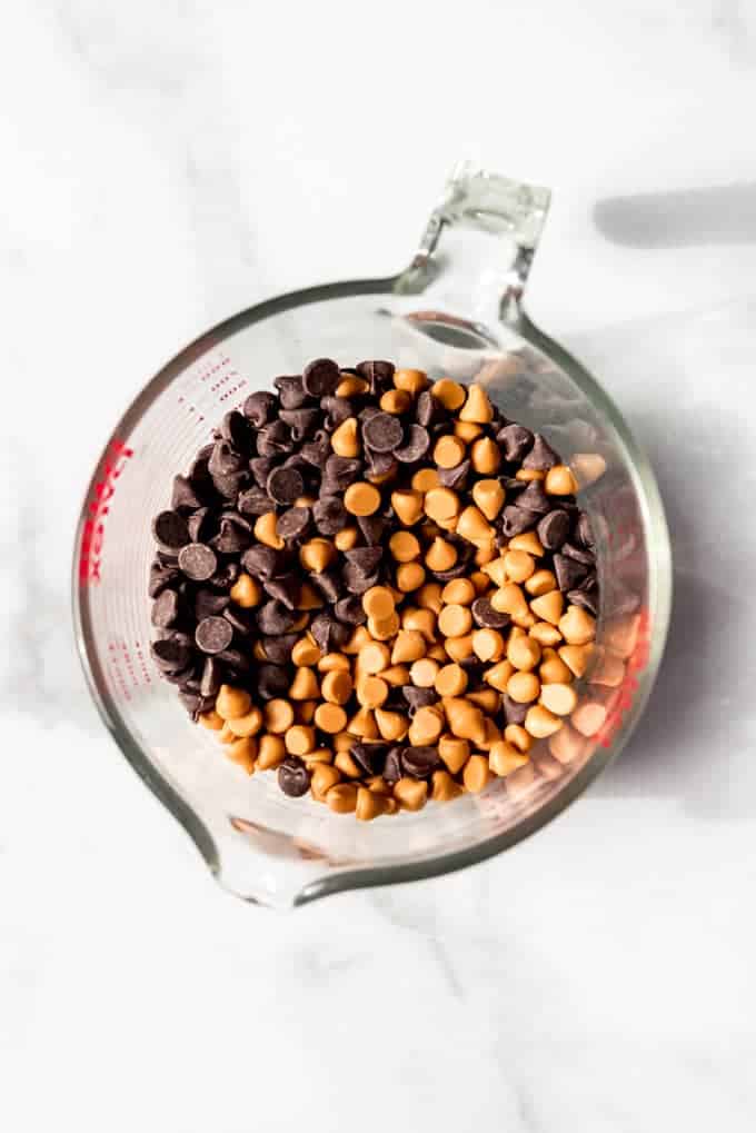 An image of butterscotch and chocolate chips in a glass measuring cup.