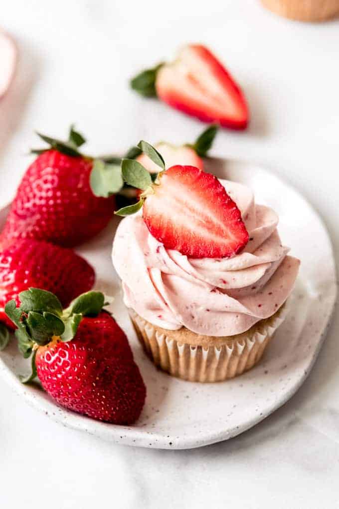An image of a strawberry cupcake on a plate with fresh strawberries.