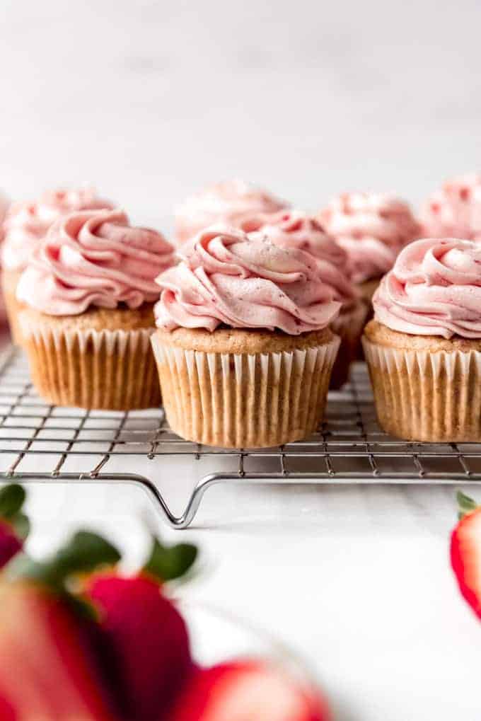 An image of cupcakes with fresh strawberry buttercream frosting swirled on top.