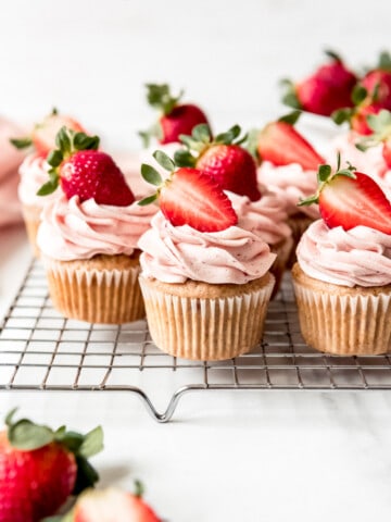 An image of fresh strawberry cupcakes with strawberries on top.