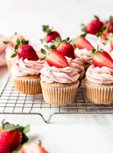 An image of fresh strawberry cupcakes with strawberries on top.