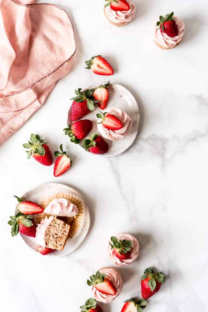 An image of strawberries and cupcakes on plates with a pink linen napkin.