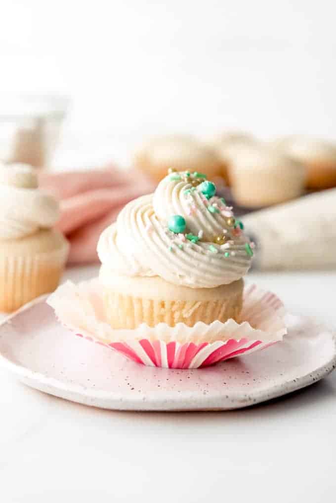 An image of a homemade vanilla cupcake with a swirl of vanilla buttercream and sprinkles.