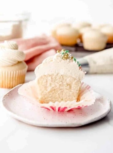 An image of a vanilla cupcake with vanilla buttercream that is cut in half.