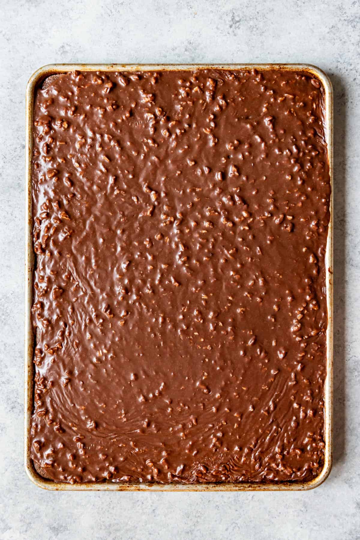 An image of a Texas sheet cake with warm chocolate pecan icing poured over the top.