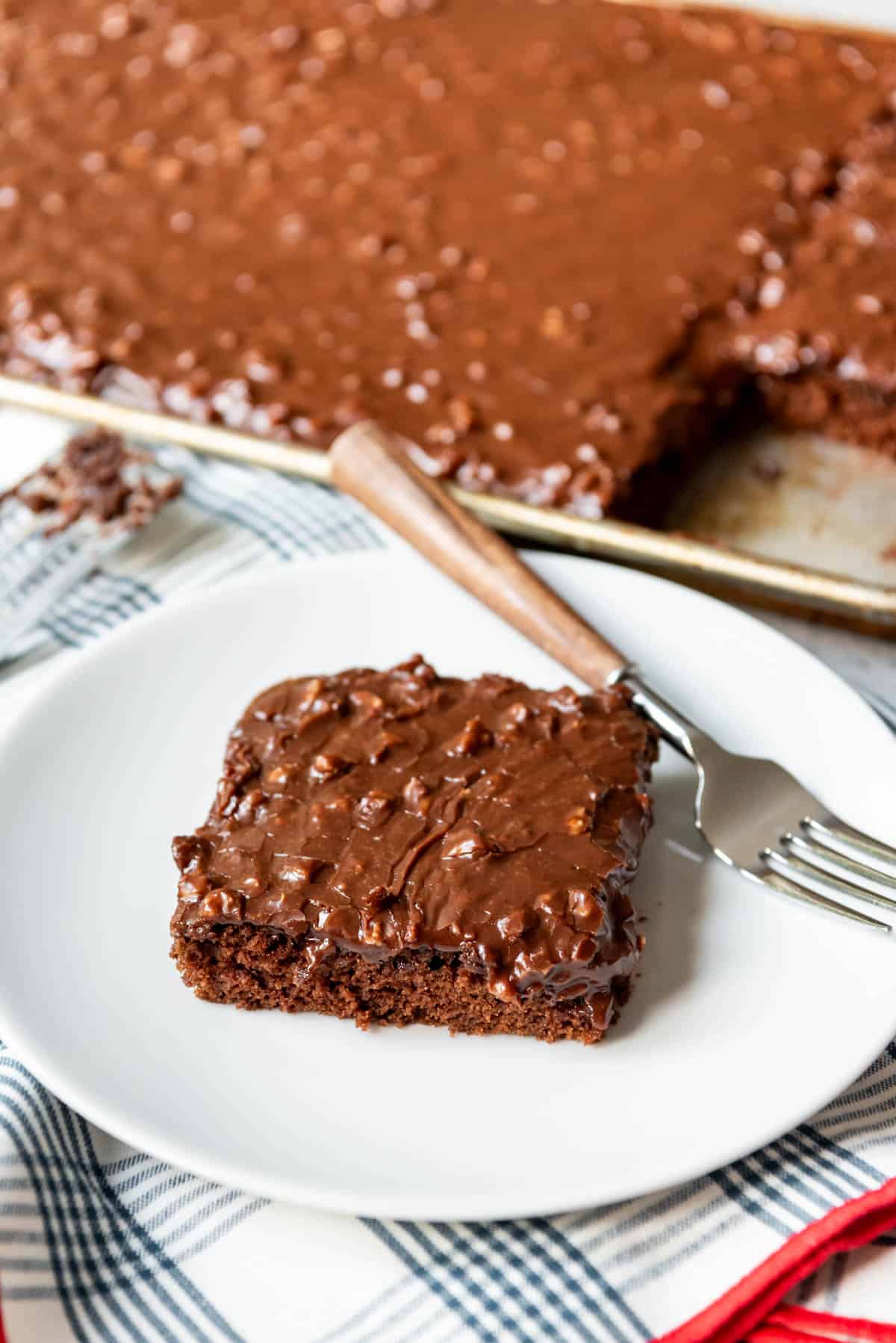 An image of a slice of chocolate sheet cake on a white plate.