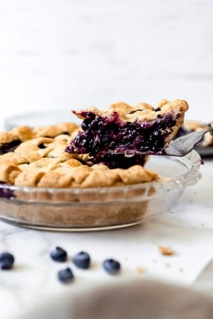 A slice of the best blueberry pie being lifted out of the pie pan.