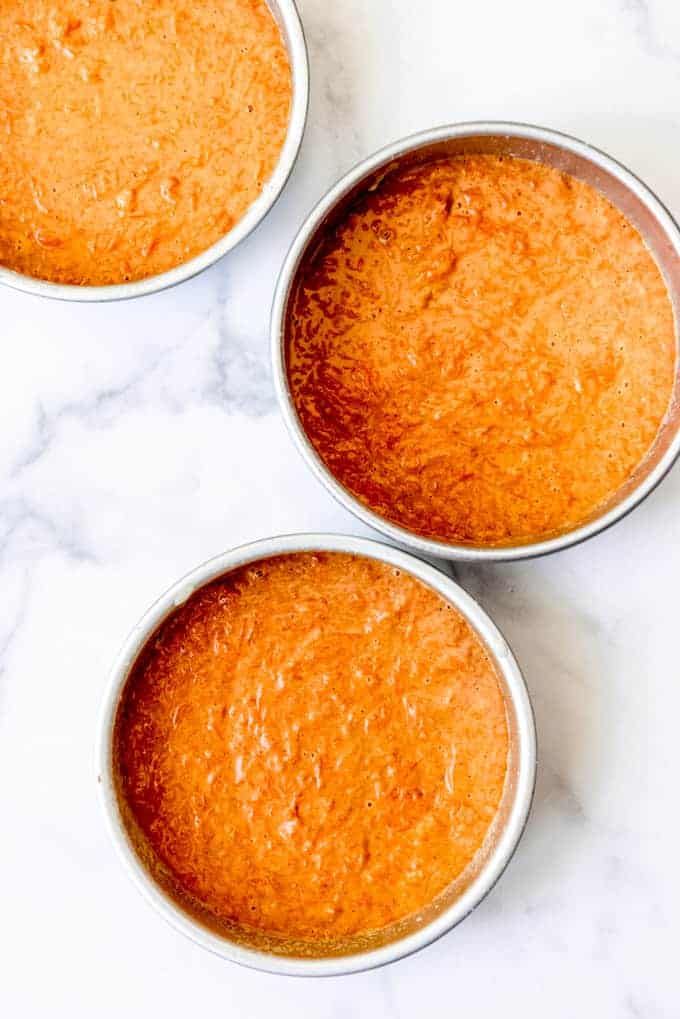 An image of carrot cake batter divided between three 8-inch cake pans.
