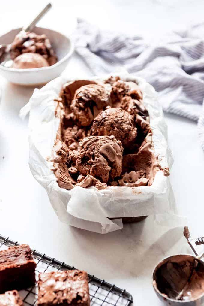 A pan full of homemade chocolate brownie ice cream with big scoops on top.