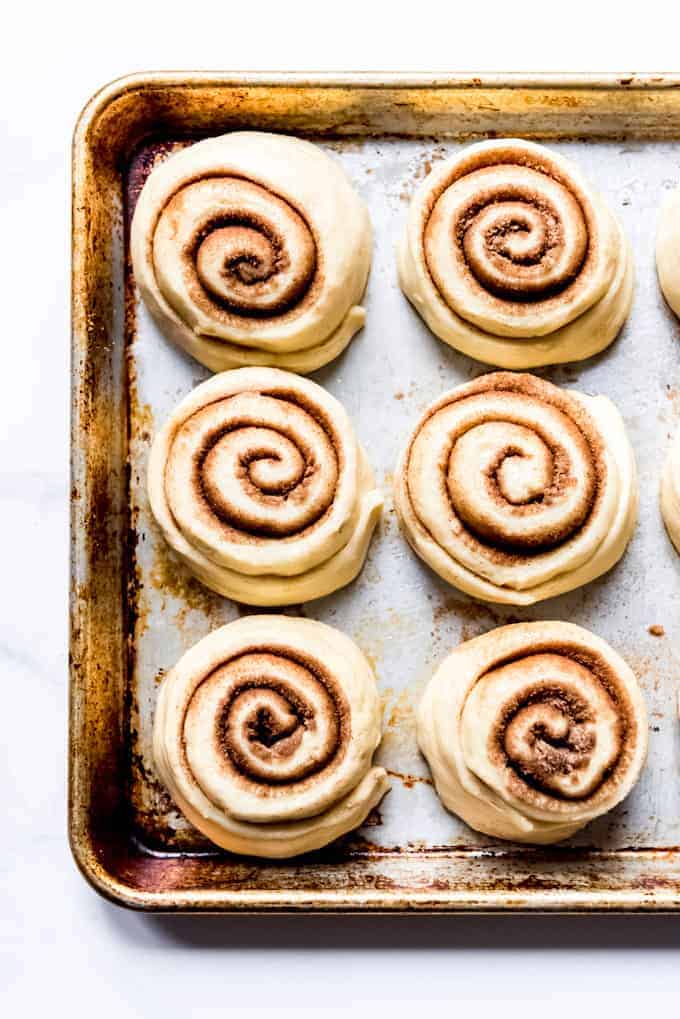 An image of yeast cinnamon rolls rising on a baking dish.