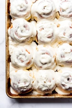 An image of a pan of frosted homemade cinnamon rolls with cream cheese icing.