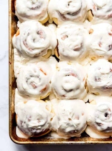 An image of a pan of frosted homemade cinnamon rolls with cream cheese icing.