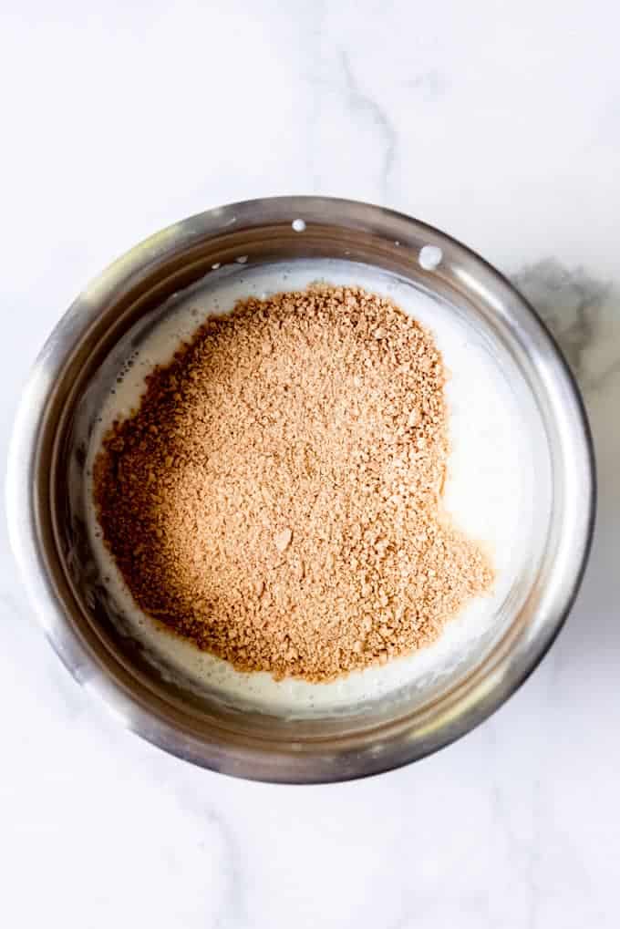 An image of graham cracker crumbs being added to a vanilla ice cream base.