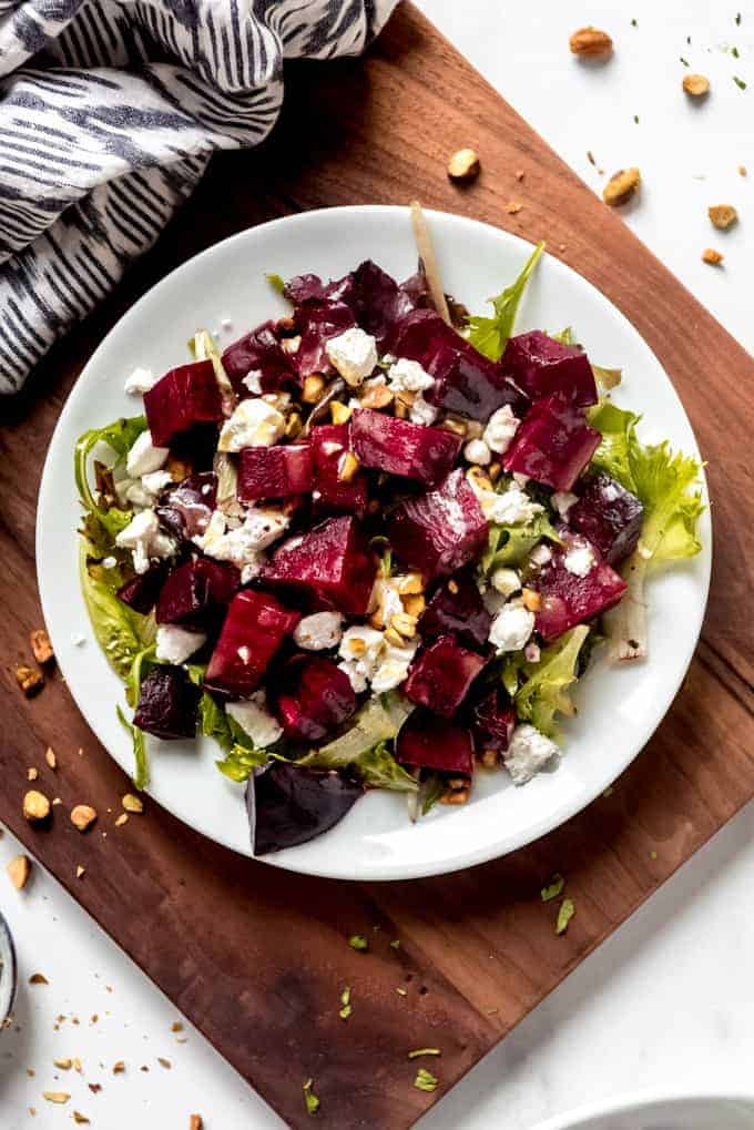 An image of a plate of roasted roasted beets, spring salad greens, goat cheese, and pistachios in a homemade vinaigrette.