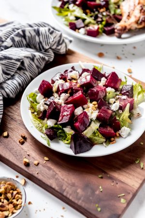An image of roasted beet salad with goat cheese and pistachios on a plate.