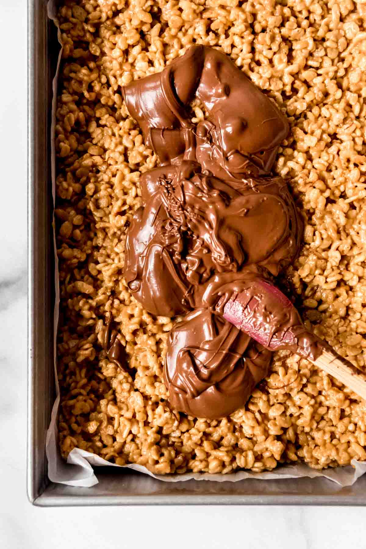 An image of melted chocolate and butterscotch chips on top of peanut butter rice krispie treats.