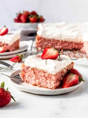 An image of a piece of strawberry cake with whipped cream cream cheese frosting.