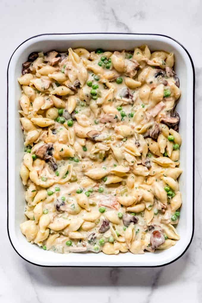 An image of pasta shells in a creamy sauce with peas, mushrooms, tuna, and onions.