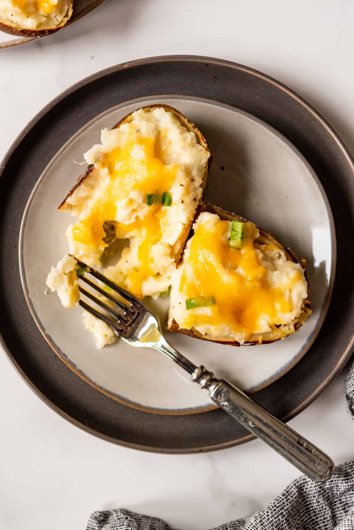 An image of a twice baked potato with cream cheese on a plate.