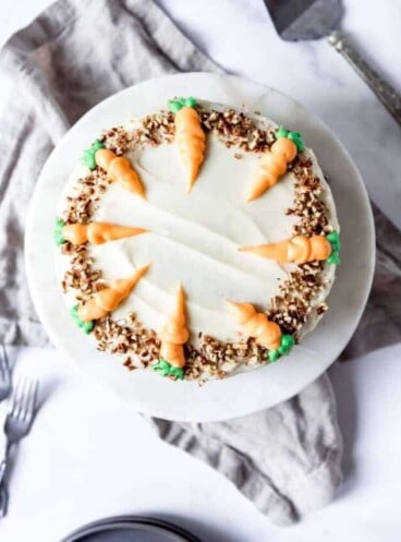 An image looking down onto the top of a carrot cake decorated with piped carrots made from frosting.