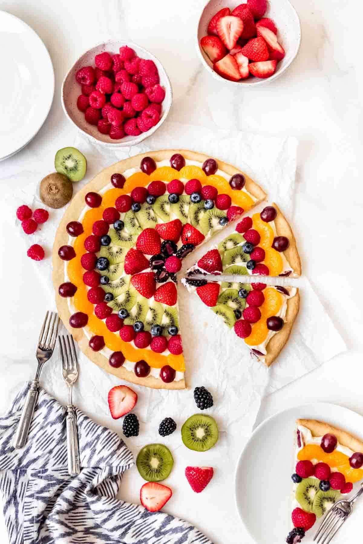 An image of a homemade fruit pizza sliced into wedges to serve.