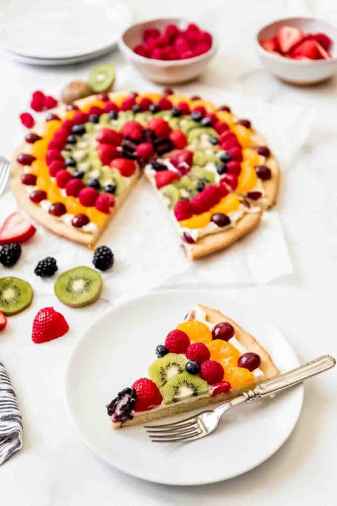 An image of a slice of fruit pizza on a white plate.