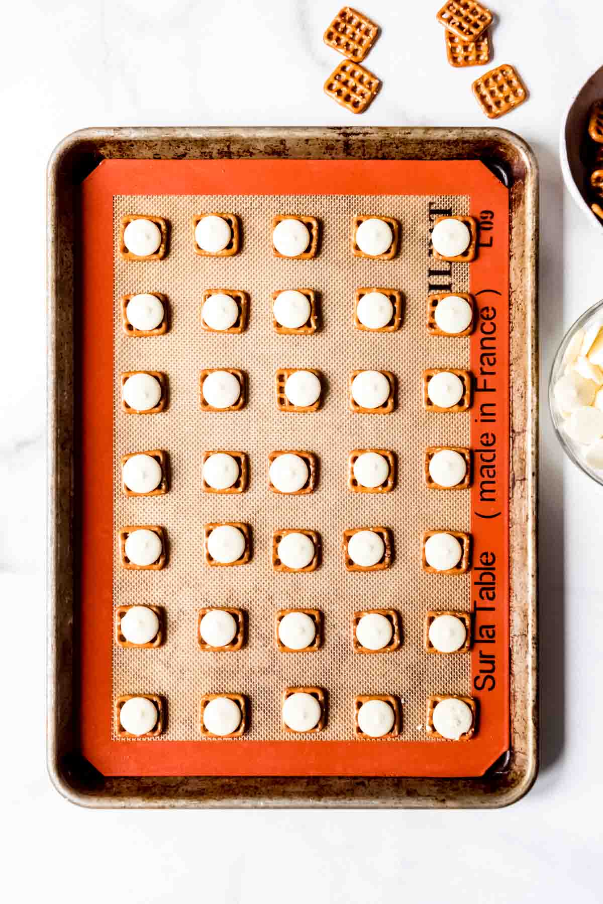 White candy melts placed on square pretzel bites.