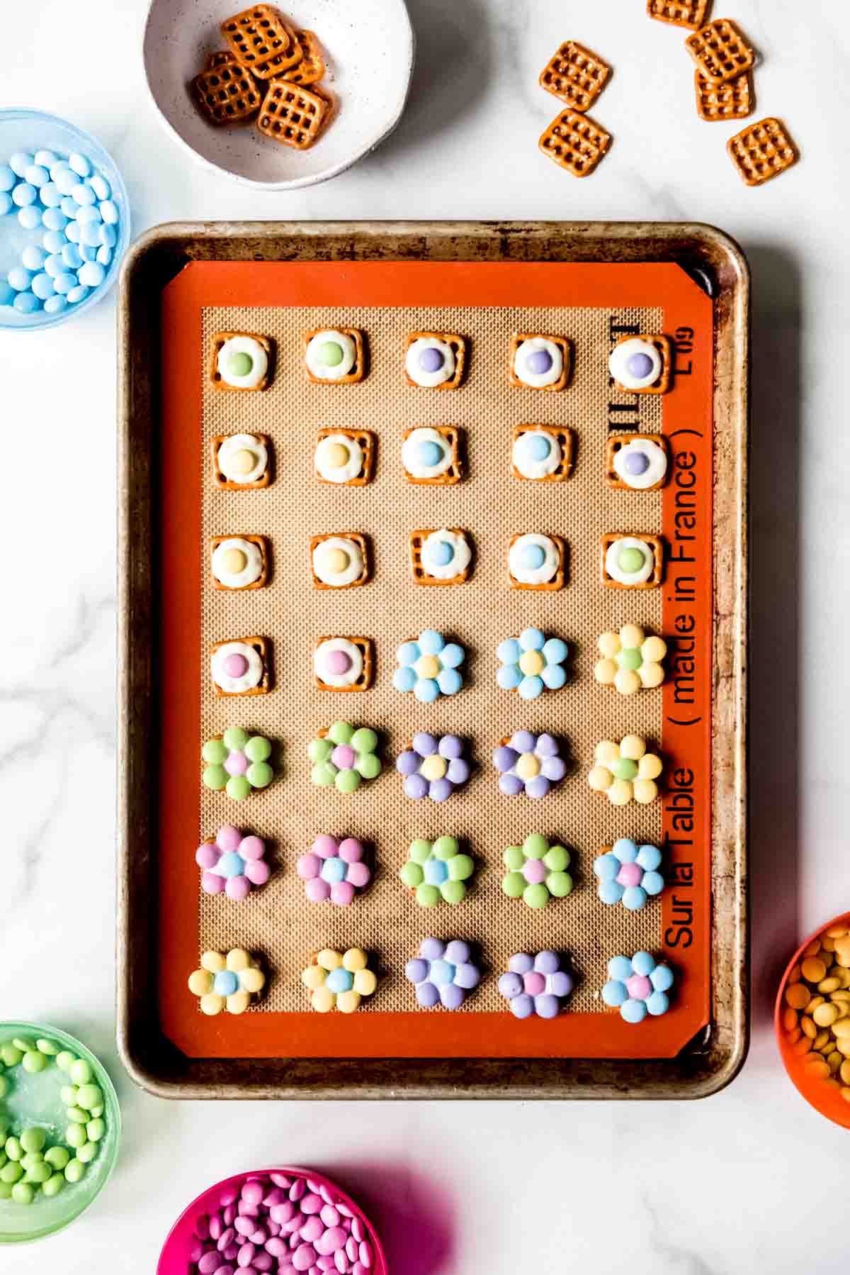 An overhead image of pretzel flower hugs being assembled on a baking sheet.