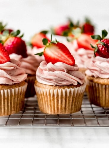 An image of strawberry cupcakes on a wire rack.