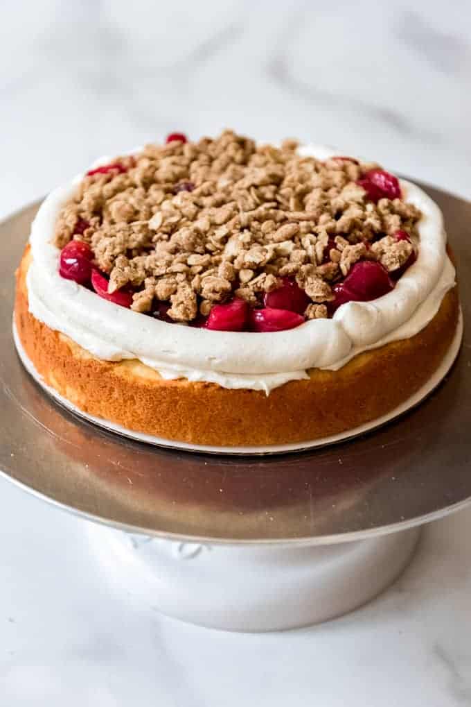 A layer of vanilla cake topped with buttercream frosting, cherry pie filling, and oat crisp.