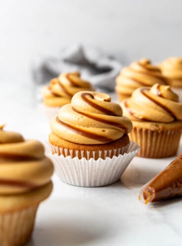 Swirled dulce de leche cupcakes on a white surface.