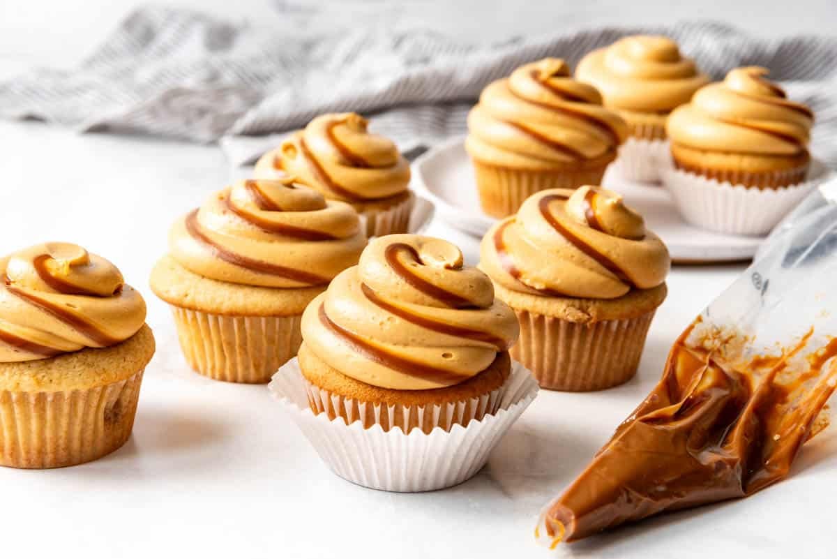 Dulce de leche cupcakes next to a piping bag filled with dulce de leche.