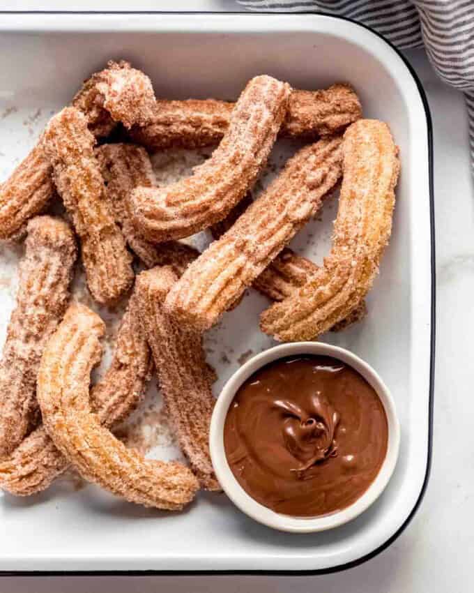 Cinnamon sugar churros in a serving dish with chocolate sauce for dipping.