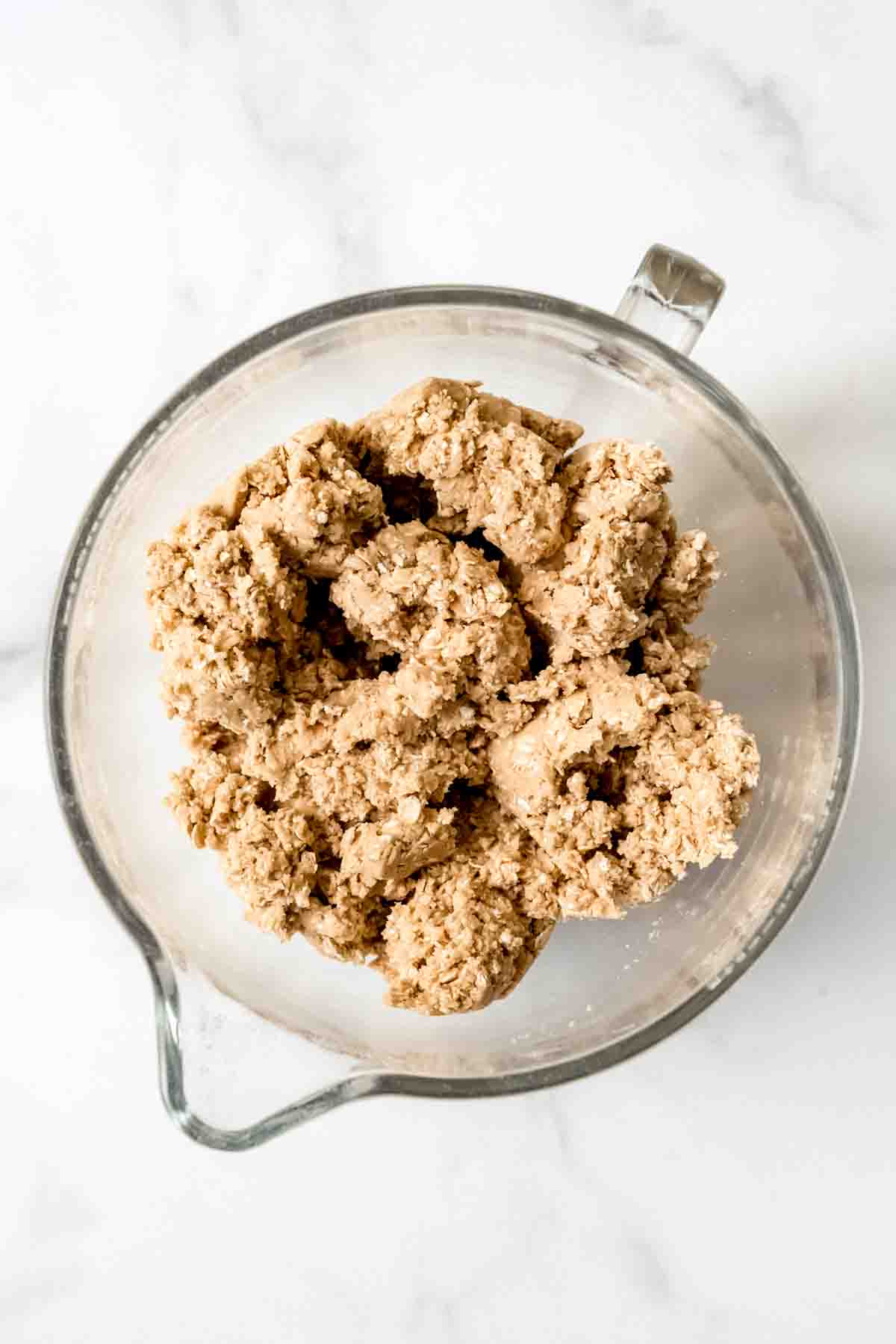 A glass mixing bowl of oatmeal cookie dough.