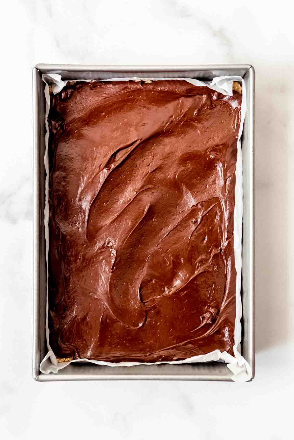 Spreading a layer of fudge into a 9x13-inch pan.