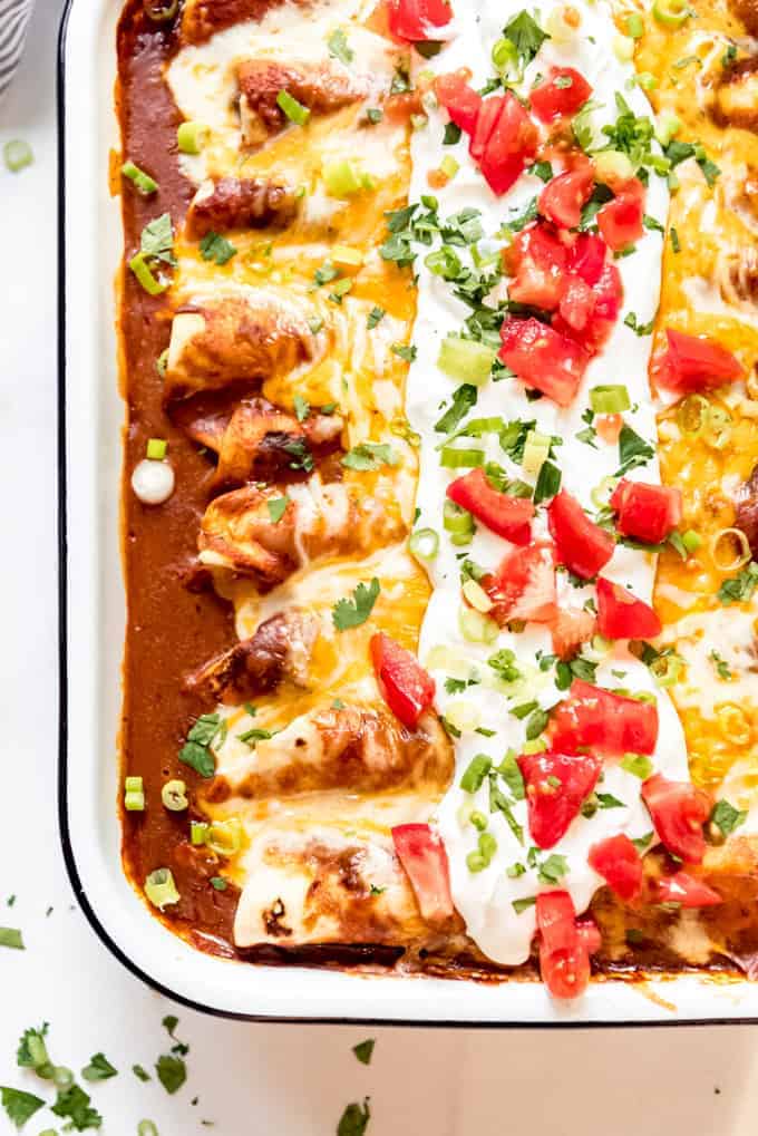 A pan of homemade enchiladas with red sauce and cheese on top.