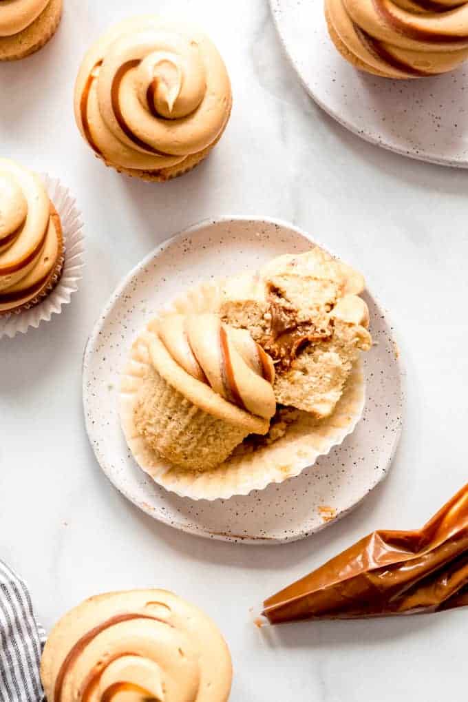 A filled cupcake that cut in half on a plate next to a bag with the filling and more cupcakes.