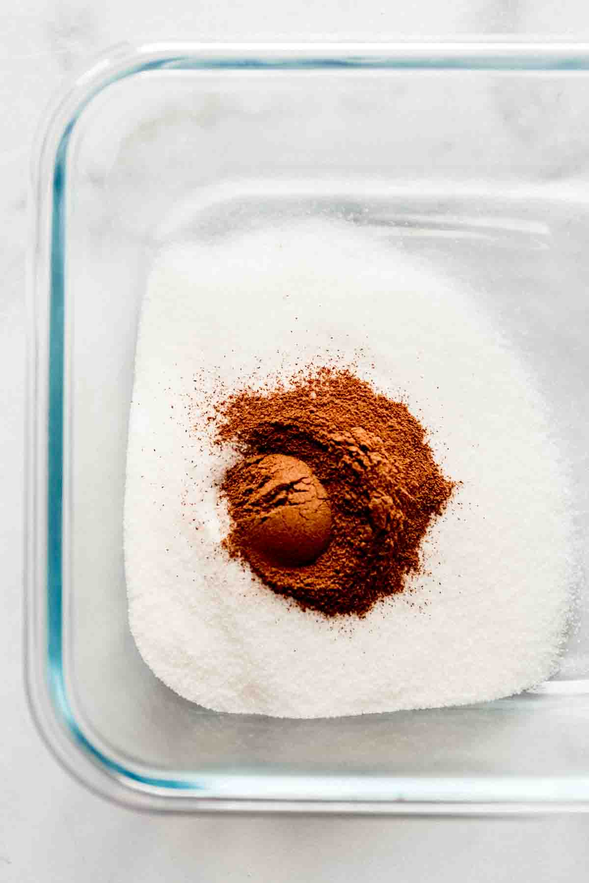 Combining cinnamon and sugar in a glass dish.