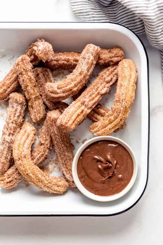 Cinnamon sugar churros in a serving dish with chocolate sauce for dipping.