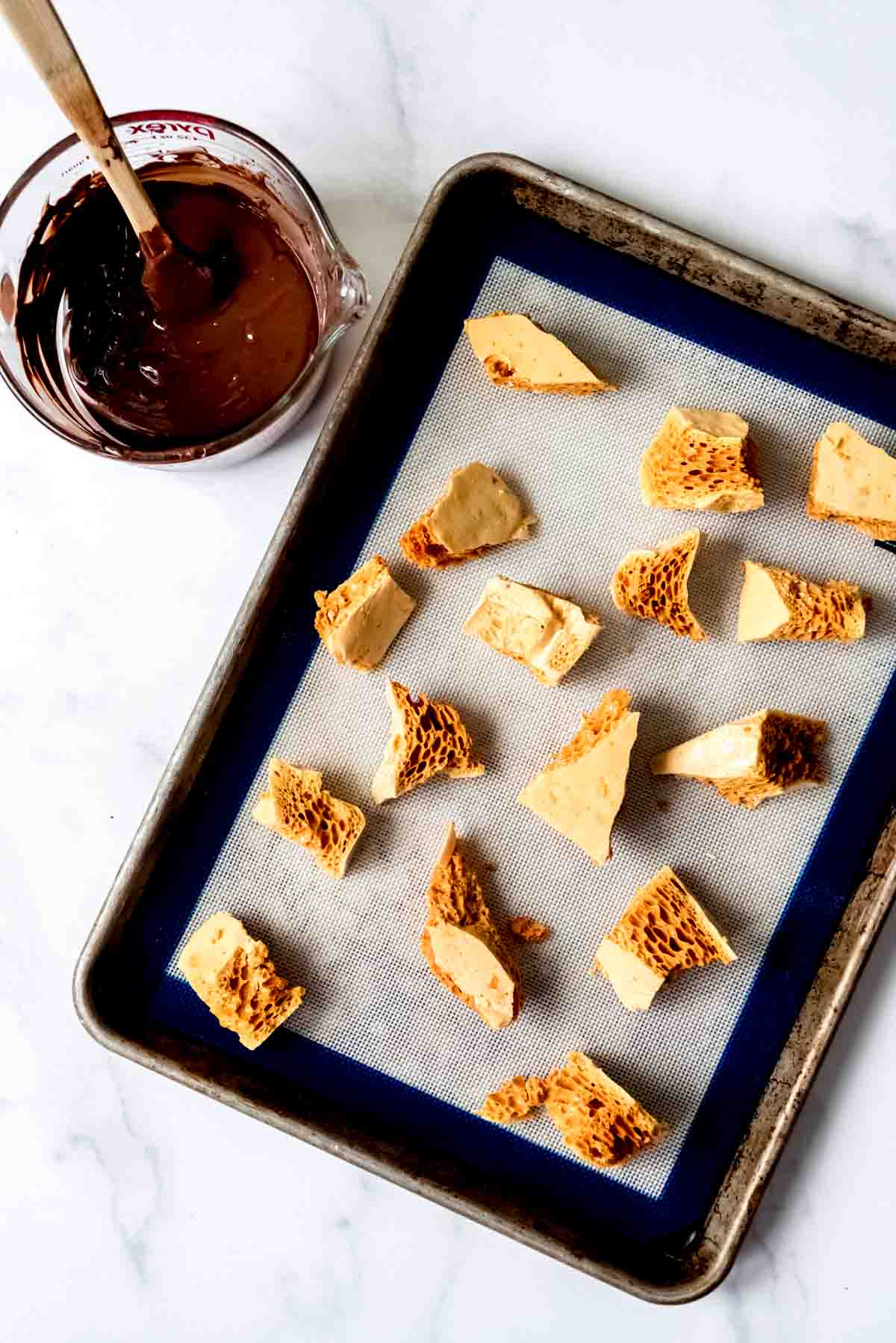 An image of crunchy honeycomb candy next to a bowl of melted dark chocolate.