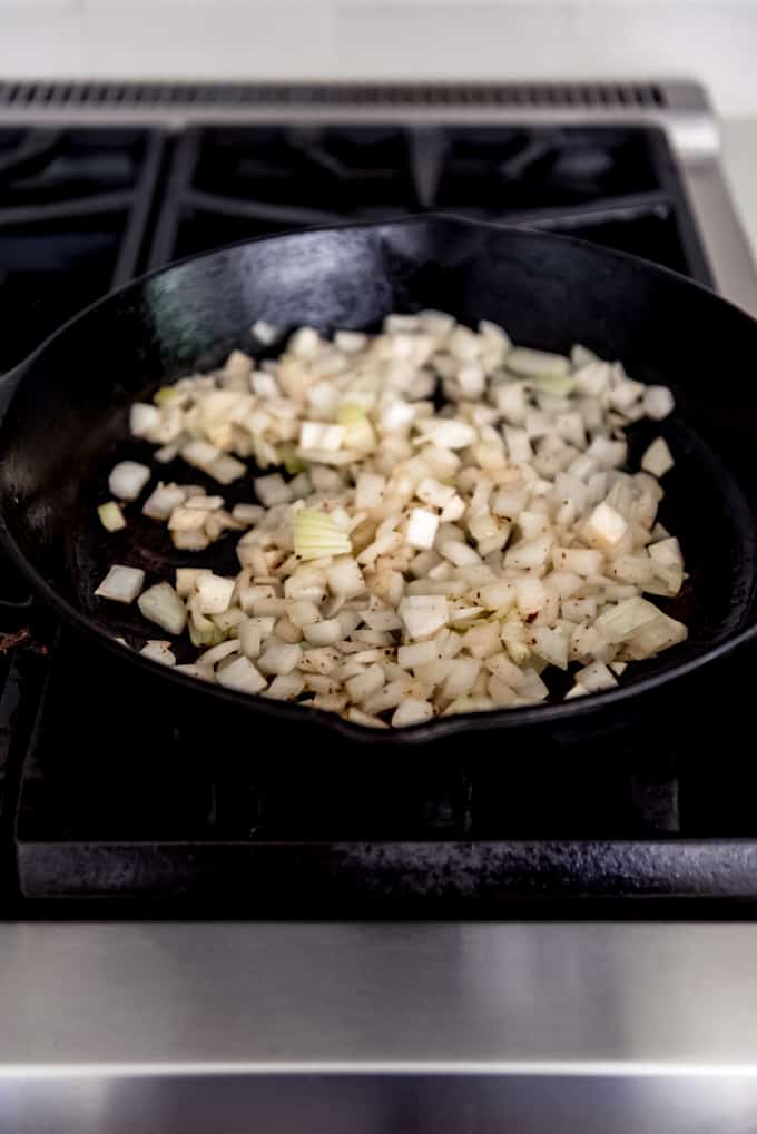 Chopped onions in a cast iron skillet on the stovetop.
