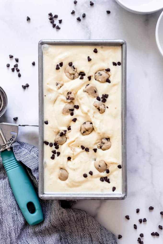 A pan filled with homemade cookie dough ice cream next to an ice cream scoop.