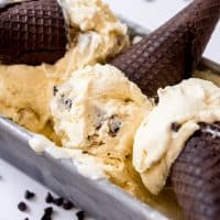Scoops of cookie dough ice cream with chocolate Oreo sugar cones in a bread pan.