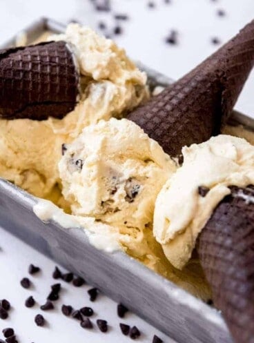 Scoops of cookie dough ice cream with chocolate Oreo sugar cones in a bread pan.